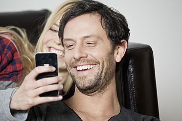 Paar schaut auf Handy, lächelnd, Nahaufnahme - FMKF000463