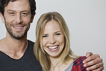 Couple smiling against white background, portrait - FMKF000461