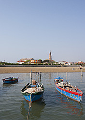 Italien, Provinz Venedig, Caorle, Tourist am Strand mit Fischerboot im Adriatischen Meer - WWF002357
