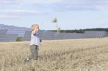 Deutschland, Sachsen, Junge läuft im Gras, Sonnenkollektoren im Hintergrund - MJF000040