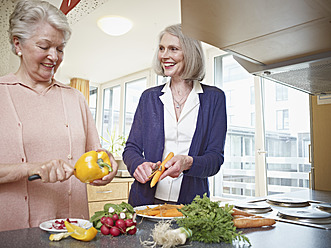 Deutschland, Köln, Seniorinnen beim Gemüseschneiden im Pflegeheim, lächelnd - WESTF018689
