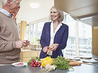 Germany, Cologne, Senior couple cutting vegetables, smiling - WESTF018690