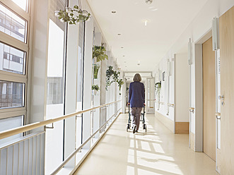 Germany, Cologne, Senior woman with walking frame at corridor in nursing home - WESTF018692