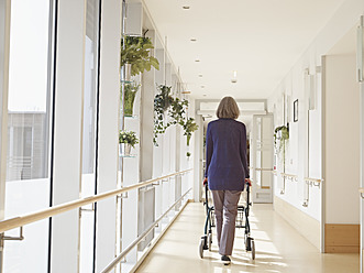 Germany, Cologne, Senior woman with walking frame at corridor in nursing home - WESTF018693