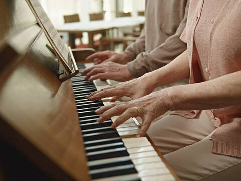 Germany, Cologne, Senior couple playing piano in nursing home stock photo