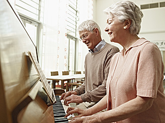 Germany, Cologne, Senior couple playing piano in nursing home - WESTF018704