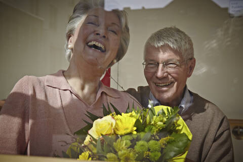 Deutschland, Köln, Älteres Paar mit Blumenstrauß, lächelnd, lizenzfreies Stockfoto