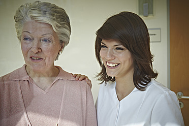 Germany, Cologne, Senior women and caretaker looking away in nursing home, smiling - WESTF018725