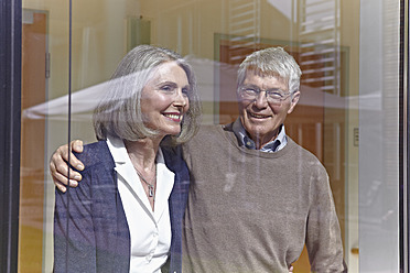 Deutschland, Köln, Älteres Paar schaut lächelnd durchs Fenster - WESTF018728