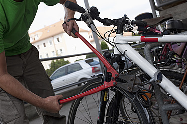 Deutschland, Bayern, München, Älterer Mann schneidet Fahrradschloss mit Bolzenschneider - DSF000612