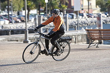 Italy, Trento, Mature man cycling through promenade - DSF000572