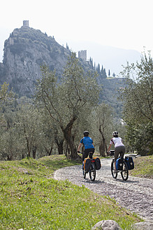Italien, Trient, Mann und Frau beim Radfahren, Schloss von Arco im Hintergrund - DSF000574