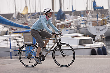 Italien, Trient, Mittlere erwachsene Frau beim Radfahren am Hafen in Riva - DSF000576