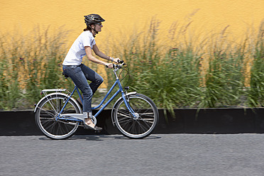 Germany, Bavaria, Munich, Mid adult woman cycling through road - DSF000601