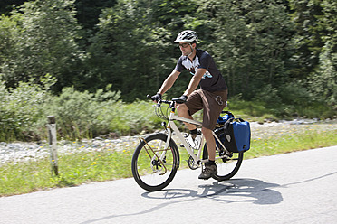 Austria, Tyrol, Young man cycling through country road - DSF000586