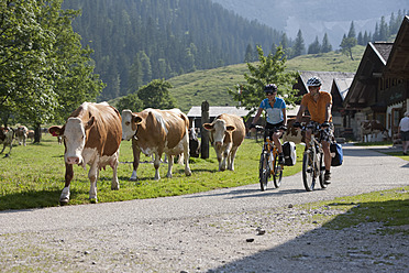 Austria, Tyrol, Man and woman cycling through road - DSF000595