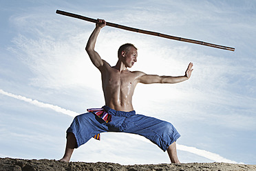 Germany, Bavaria, Young man doing martial arts training with stick - MAEF004664