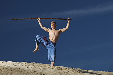 Germany, Bavaria, Young man doing martial arts training with stick - MAEF004677