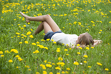 Austria, Teenage girl lying in field of flowers - WWF002372