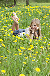 Österreich, Teenager-Mädchen im Blumenfeld liegend, lächelnd - WWF002374