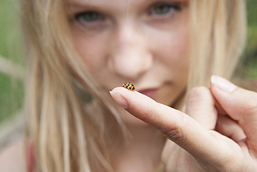 Austria, Teenage girl looking at ladybird on her finger - WWF002377