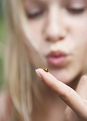 Austria, Teenage girl looking at ladybird on her finger - WWF002378