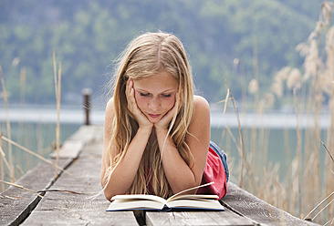 Österreich, Jugendliches Mädchen liegend und Buch lesend auf Steg - WWF002387