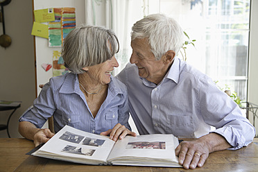 Germany, Bavaria, Senior couple with photo album, smiling - TCF002567
