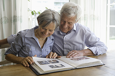 Germany, Bavaria, Senior couple with photo album, smiling - TCF002568