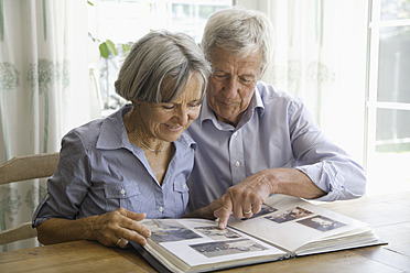 Germany, Bavaria, Senior couple with photo album, smiling - TCF002569