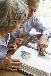 Deutschland, Bayern, Seniorenpaar mit Fotoalbum, lächelnd - TCF002574