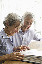 Germany, Bavaria, Senior couple with photo album, smiling - TCF002576