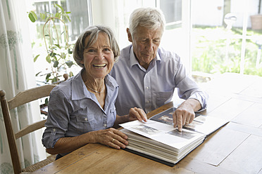 Germany, Bavaria, Senior couple with photo album, smiling - TCF002578