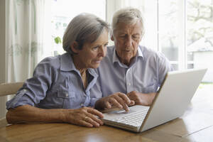 Deutschland, Bayern, Älteres Paar benutzt Laptop zu Hause - TCF002591