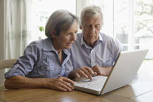 Germany, Bavaria, Senior couple using laptop at home - TCF002591