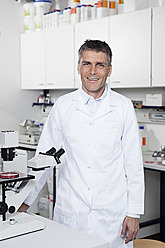 Deutschland, Bayern, München, Wissenschaftlerin mit Mikroskop im Labor, Porträt - RBF000855