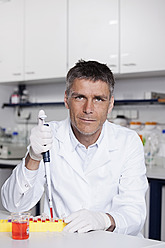 Deutschland, Bayern, München, Wissenschaftlerin gießt rote Flüssigkeit mit Pipette für medizinische Forschung in Labor - RBF000856