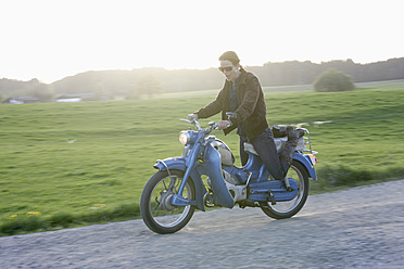 Germany, Bavaria, Mature woman riding old moped of 1960s - TCF002600