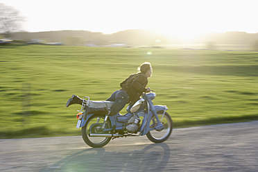 Germany, Bavaria, Mature woman riding old moped of 1960s - TCF002598