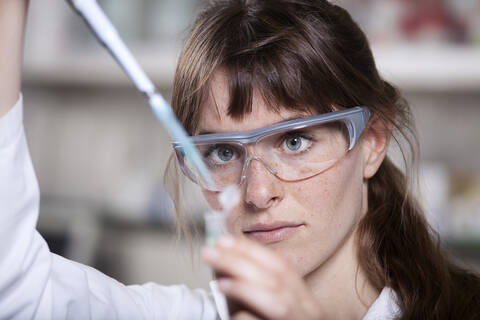 Deutschland, Bayern, München, Wissenschaftlerin mit Pipette und Reagenzglas im Labor, lizenzfreies Stockfoto