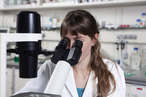 Deutschland, Bayern, München, Wissenschaftlerin mit Mikroskop im Labor, lizenzfreies Stockfoto