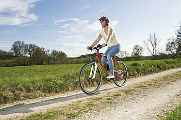 Deutschland, Bayern, Ältere Frau fährt Elektrofahrrad - RNF000938