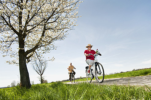 Deutschland, Bayern, Seniorenpaar auf Elektrofahrrad - RNF000950