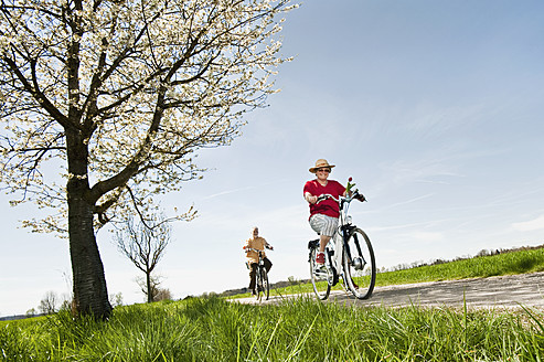 Germany, Bavaria, Senior couple riding electric bicycle - RNF000950