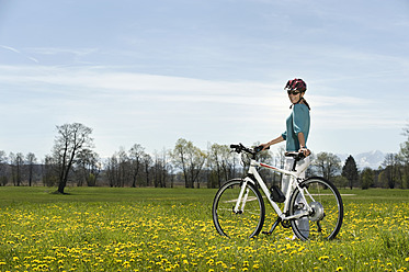 Deutschland, Bayern, Mittlere erwachsene Frau fährt Elektrofahrrad - RNF000951