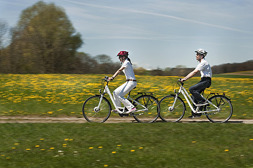 Germany, Bavaria, Man and woman riding electric bicycle - RNF000953