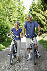 Germany, Bavaria, Senior couple with bicycle, smiling - TCF002630
