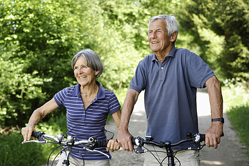 Germany, Bavaria, Senior couple with bicycle, smiling - TCF002631