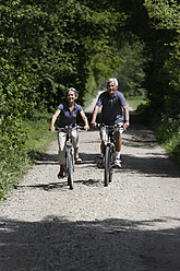 Germany, Bavaria, Senior couple cycling through single track - TCF002643