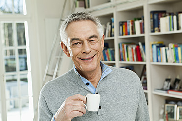 Germany, Berlin, Senior man with coffee cup, smiling, portrait - FMKYF000006